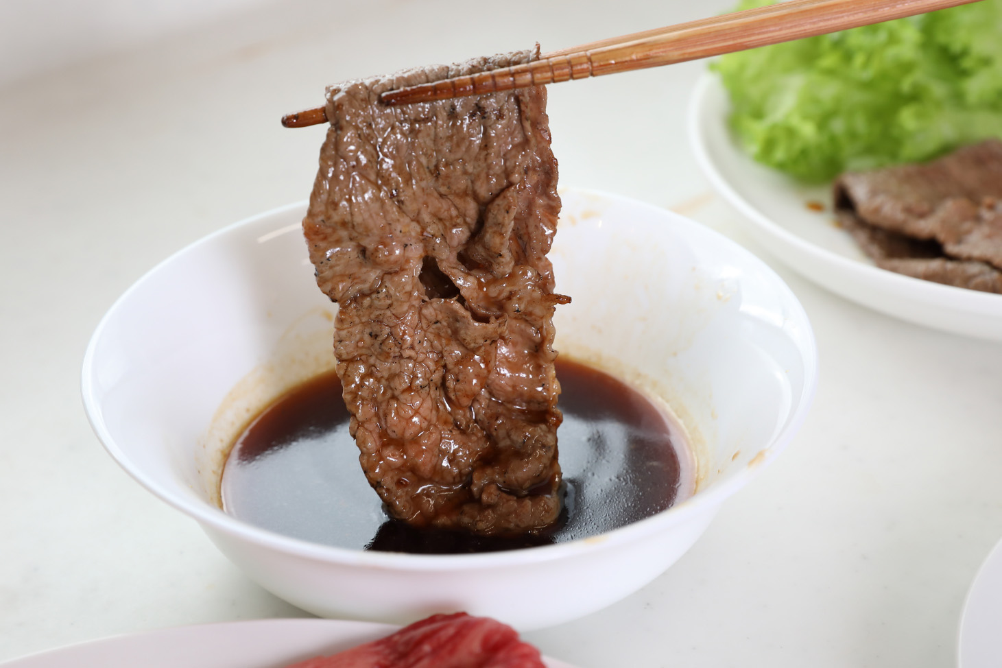炙り焼きの肉にタレを潜らせる